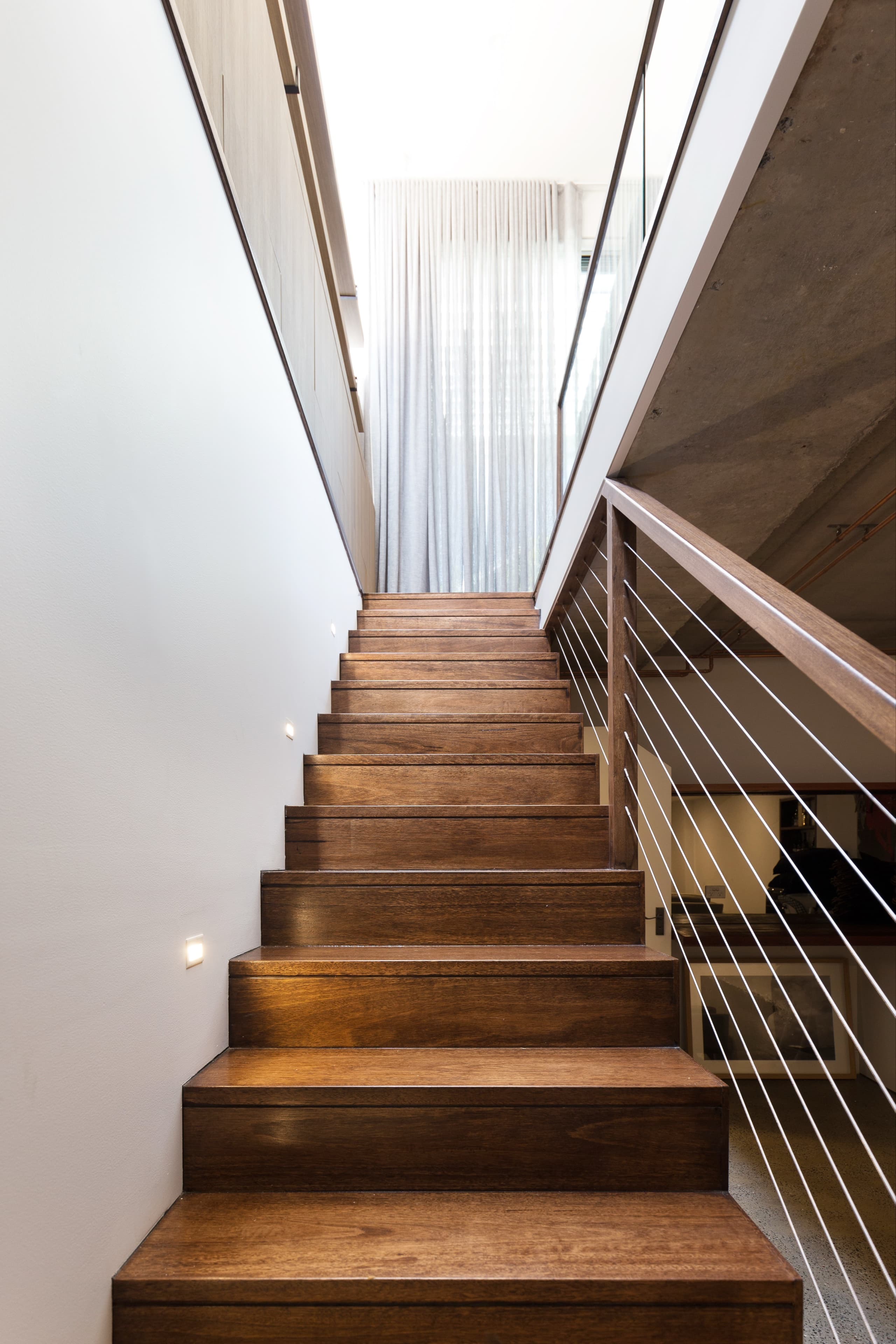 KBLCO living room, Sydney. Timber open-tread stair with a cable balustrade.