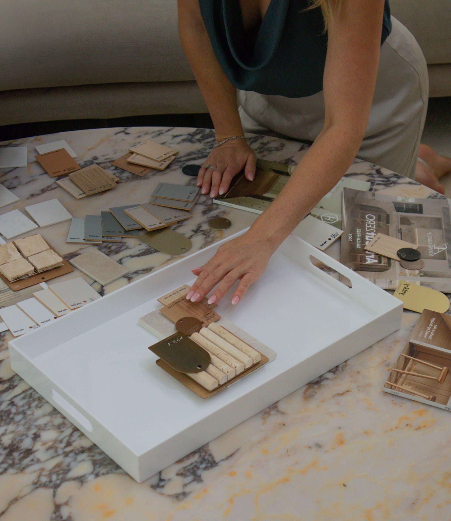 A member of the studio arranging stone and timber finishes in the sample tray.