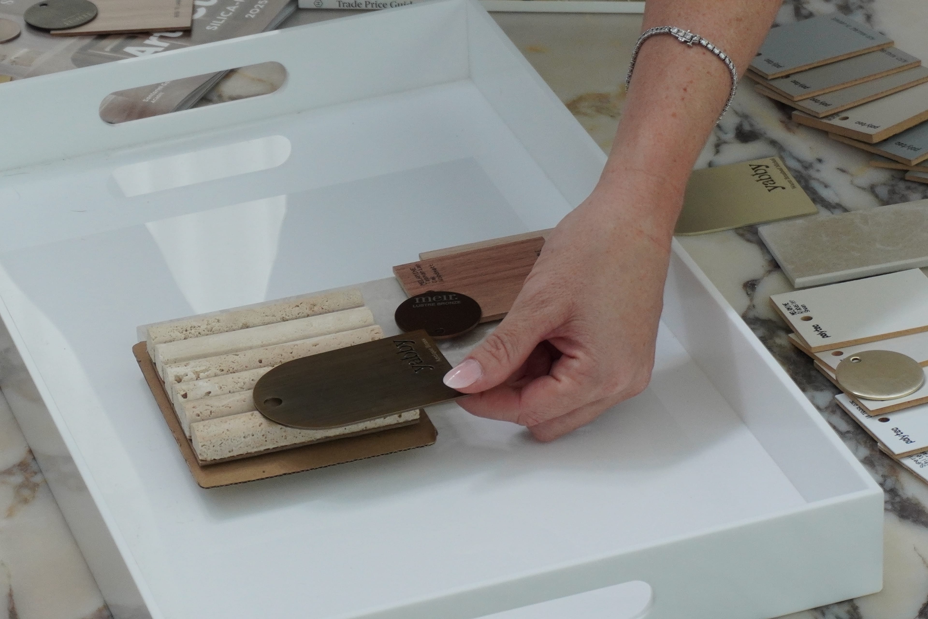 A member of the studio selecting stone and brass finishes from the tray.