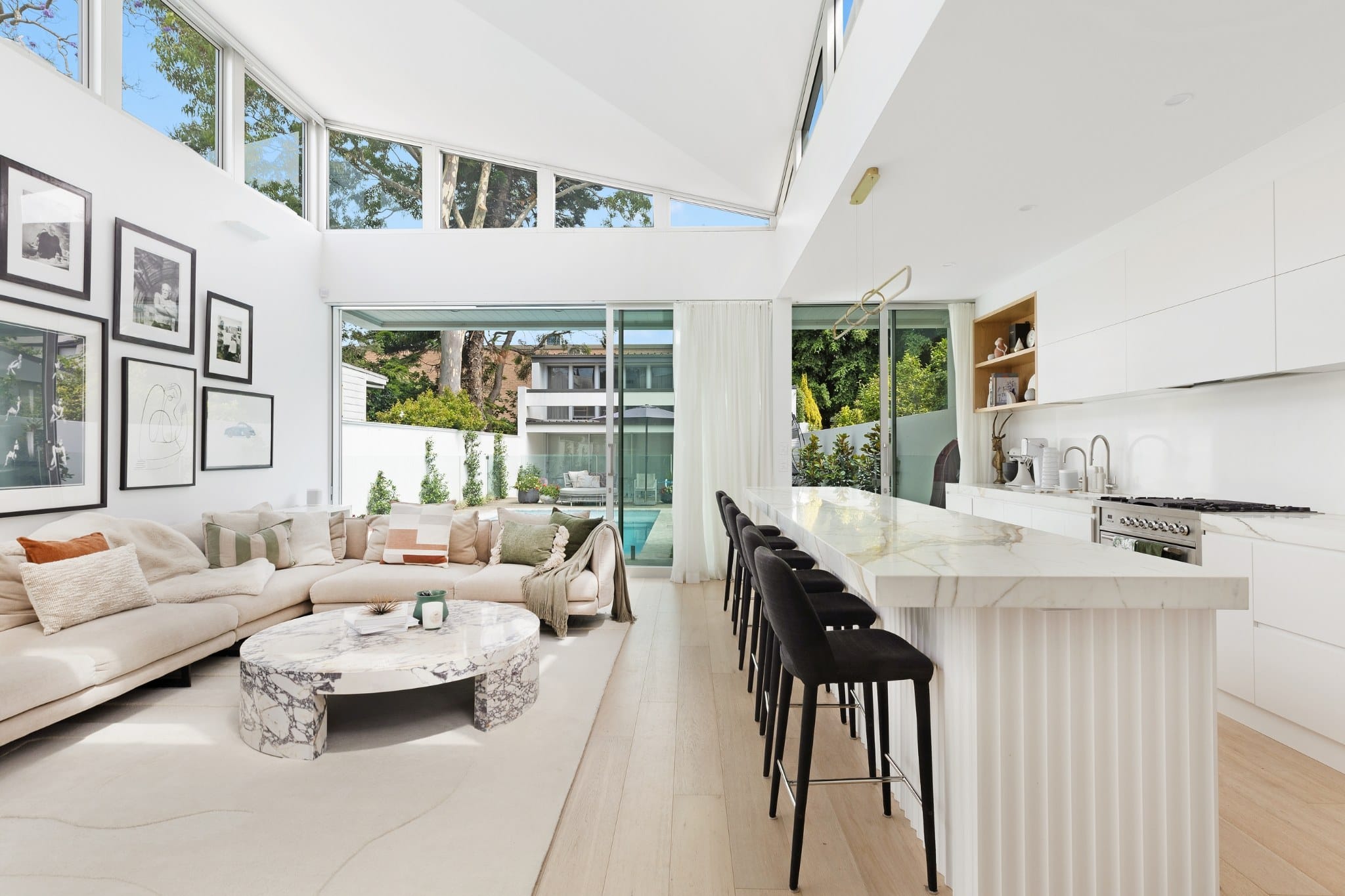 Open-plan living and kitchen by KBL Collective Co, vaulted ceiling and marble island in a Sydney home