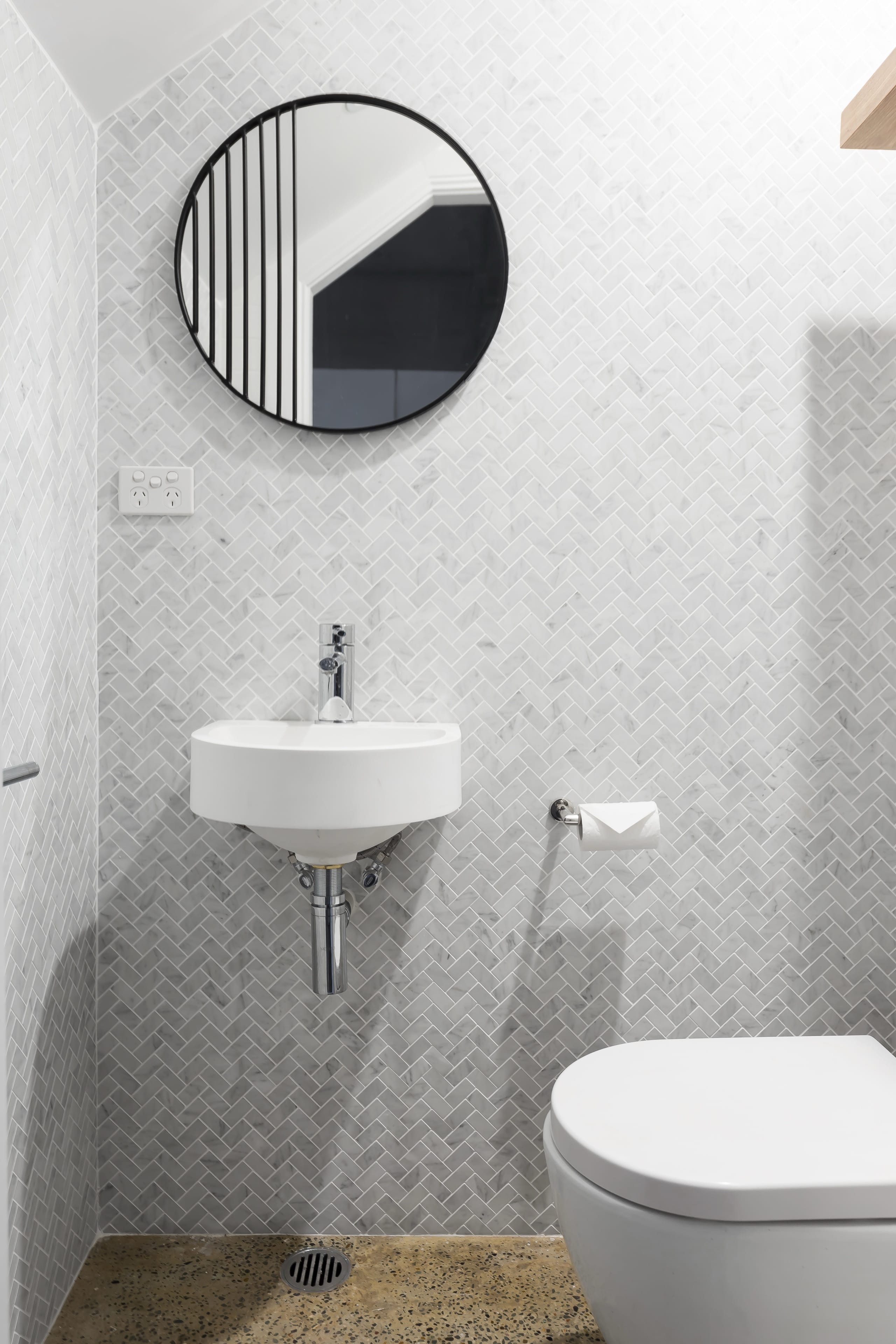 Johnston powder room with a round mirror and dark joinery.